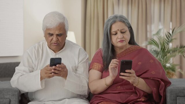 Old Indian couple busy in their phones