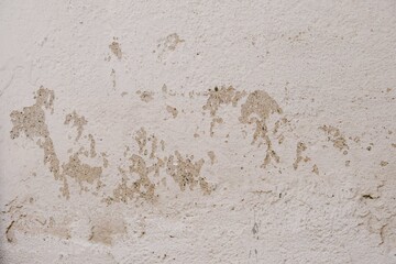 Old white wall with peeling paint, grunge background