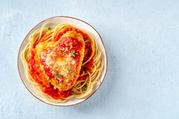 Chicken Parmesan, Italian pasta dish. Breaded chicken breast with cheese and spaghetti with tomato sauce, shot from above on a stone background with copy space