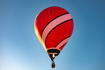Fototapeta premium A hot air balloon that's so bright and colorful, with a red and black design that stands out against the clear blue sky. It's like a symbol of adventure and freedom