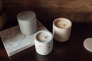 Aromatic premium soy candles in gray and pink concrete jar on wood background. Banner for candle shop. Mock up
