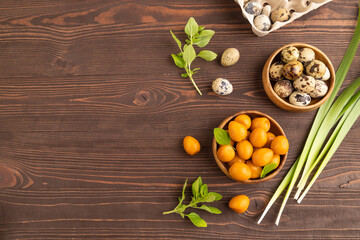 Pile of smoked quail eggs in bowl on a brown wooden background. top view, copy space.