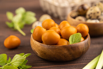 Pile of smoked quail eggs in bowl on a brown wooden. side view, selective focus.