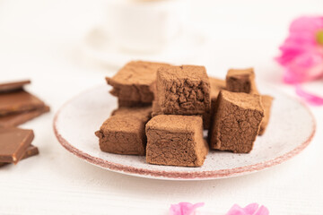 Chocolate marshmallow with cup of coffee on white wooden. side view, selective focus