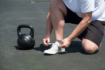 Naklejka premium Sportive man workout with kettlebell outdoor in spring or summer