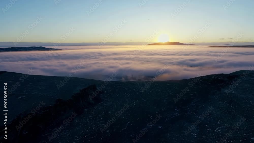 Poster lowlying clouds hug the rugged tundra creating a serene atmosphere just before the break of day.