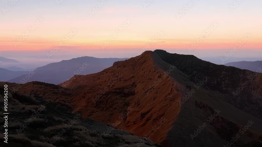 Canvas Prints As the sky slowly changes from dark blue to shades of soft pink and orange the mountainside is bathed in a warm golden light.