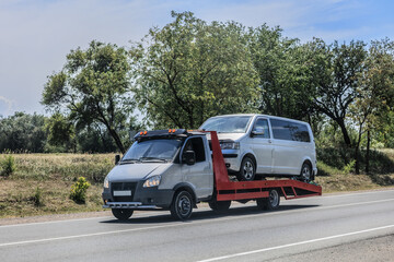 tow truck transports a minibus along a country road