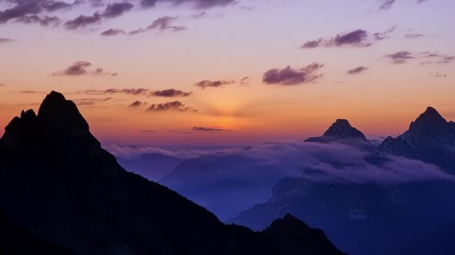 The rocky peaks stand tall and proud as the sun bids farewell in a dazzling display of colors.