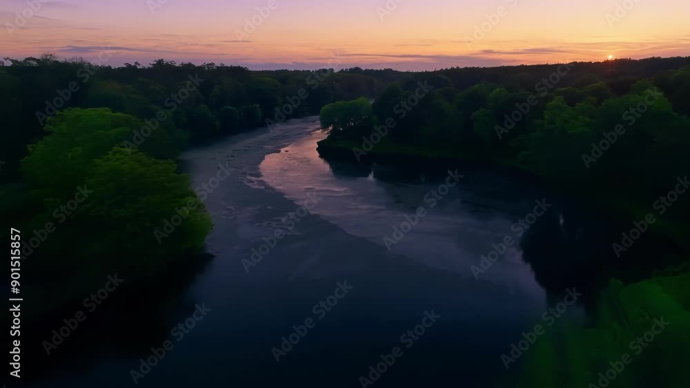 Poster The lush greenery surrounding the river gradually melds into mysterious shadows as the sun dips below the horizon.