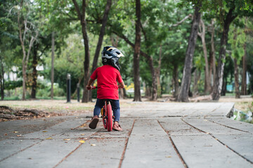 Fototapeta premium Little preschool boy playing with balance bike in tree park