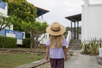 Back view of cute little fashionable girl walking in Greece village streets