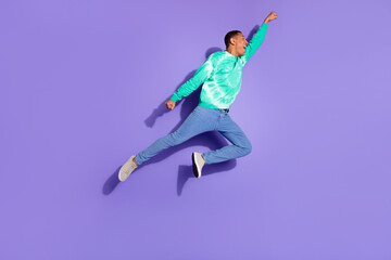 Obraz premium Full length photo of excited good mood guy wear teal sweatshirt jumping high emtpy space isolated purple color background