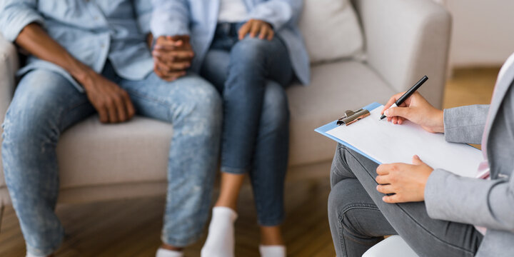 Unrecognizable man and woman holding hands during a psychotherapy session or adoption interview. Panorama, selective focus