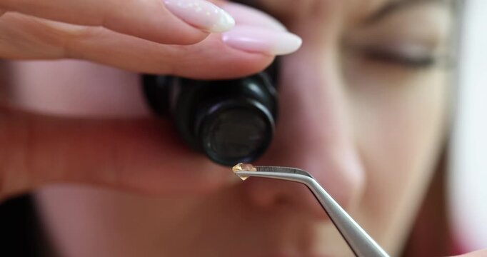Woman uses jeweler magnifier tool assessing small diamond