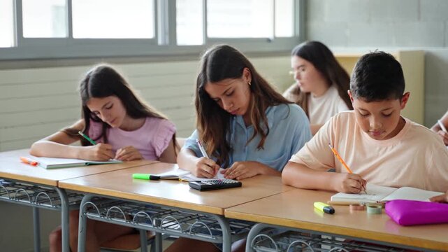 Hispanic primary school boy and girls writing exercise in classroom at the elementary school - Children Education 