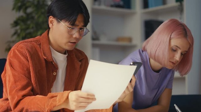 Sad multiracial couple calculating family budget at home, lack of money, debt