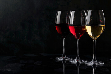 Set of wine glasses with red, white and rose wines on a black background. Concept template for advertising wineries, wine brand, restaurants and family with place for text