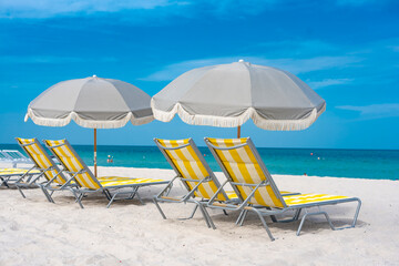 Light gray parasol and yellow Chaise lounges by the beachfront at Miami Beach.