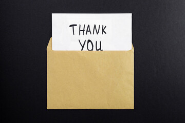 Top view of a kraft paper envelope with “Thank You!” written on a black background.