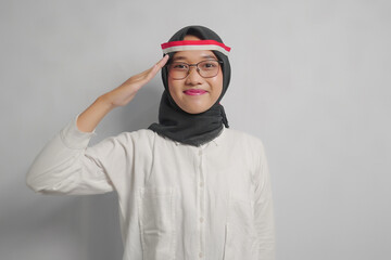 Woman Wearing a Hijab and Glasses Saluting with the Indonesian Flag on Her Head