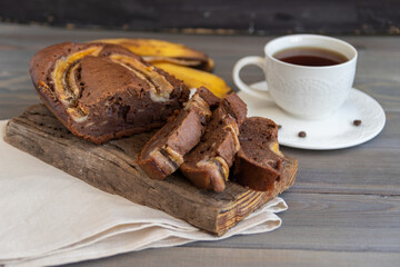 Homemade banana bread on a wooden board on a white table. The concept of breakfast and dietary nutrition.