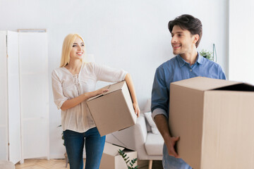Moving House. Happy Couple Carrying Packed Boxes Entering New Home. Selective Focus