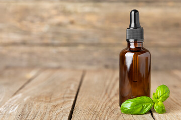 Basil essential oil on a textured wooden background. Basil essential oil and fresh leaves. Aromatherapy. Aroma oil. Medical herbs. Alternative medicine. Place for text. Copy space.