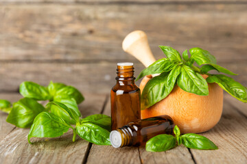 Basil essential oil on a textured wooden background. Basil essential oil and fresh leaves. Aromatherapy. Aroma oil. Medical herbs. Alternative medicine. Place for text. Copy space.