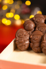 Chocolates in the shape of Christmas figures on the background of a flashing garland