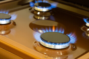 Close up shot of blue fire from domestic kitchen stove top. Gas cooker with burning flames of...