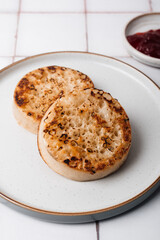 Hot Toasted Crumpets with on a plate with strawberry jam nearby. Perfect tasty breakfast