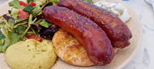 traditional greek dish with sausage, pure, vegetables and bread