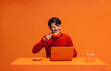 Entrepreneur enjoying coffee in vibrant monochromatic office setting with bold orange tones and stylish design