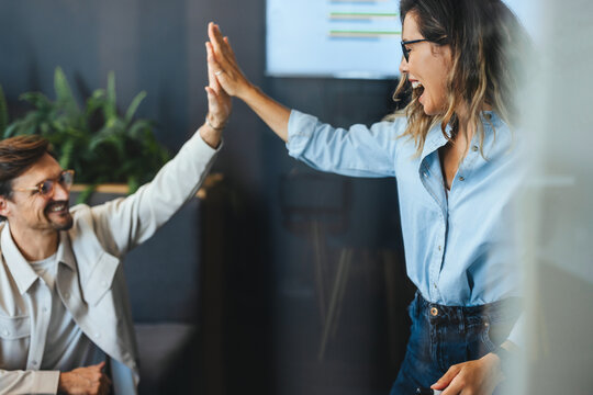 Business colleagues high fiving each other, celebrating teamwork and success