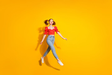 Photo portrait of young red hair funky positive girl wearing blouse and jeans running jumping carefree isolated on yellow color background