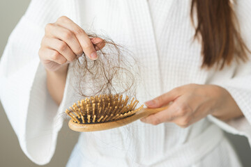 Stress asian young woman, girl hand holding comb show her hairbrush with loss, hair in brush after brushing, hair fall out problem. Health care, beauty with treatment concept, isolated on background.