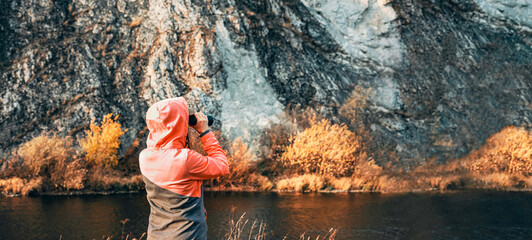 Woman looking through binoculars exploring the great outdoors in autumn Birdwatching near a river...
