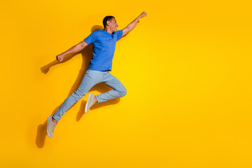 Full size photo of pretty young male flying superhero wear trendy striped outfit isolated on yellow...