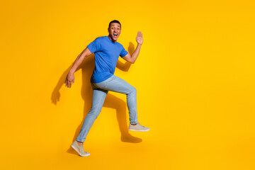 Fototapeta na wymiar Full size photo of pretty young male running excited wear trendy blue outfit isolated on yellow color background