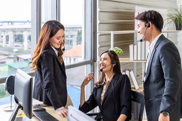 Happy call center agents enjoying teamwork in modern office. Asian man and woman.