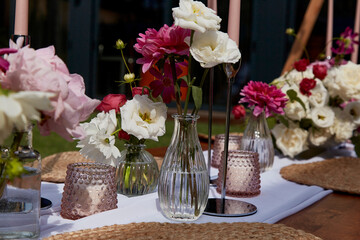 Elegant table setting with variety of fresh flowers and dishware. Visual table setting, event planning and aesthetic design for summer party picnic.