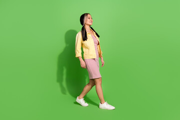 Full body portrait of pretty young woman walk empty space wear jacket dress isolated on green color background
