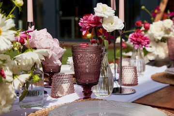 Picnic aesthetics table setting, flowers arrangement. Decorating table with white and pink blooms. Outdoor entertaining and decoration