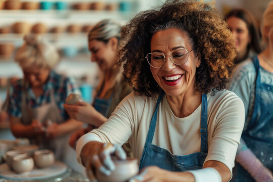 Smiling woman wearing apron shaping clay in a pottery class with others working in the background. Concepts of creativity, craftsmanship, and community engagement.