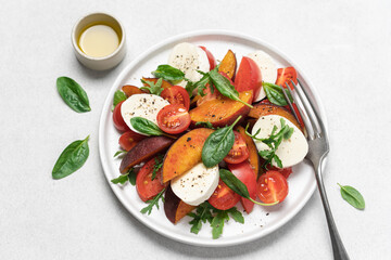 Peaches, tomatoes, mozzarella salad in plate on  white background. Caprese italian traditional salad top view