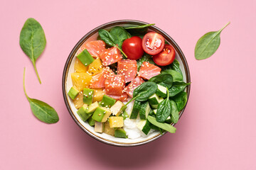 Salmon bowl with spinach, rice, avocado, tomato, cucumbers on pink background, top view. Poke bowl, healthy eating