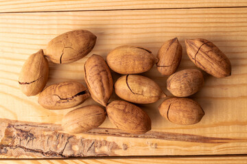 Several unshelled pecan nuts on a wooden table, macro, top view.