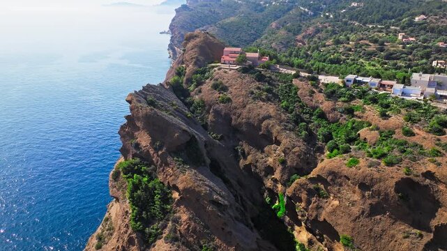 Aerial view of a Botanical garden with Snug Cove framed by rugged cliffs in Parc du Mugel. View from above of swimming off a pebble beach with turquoise clear water in France.