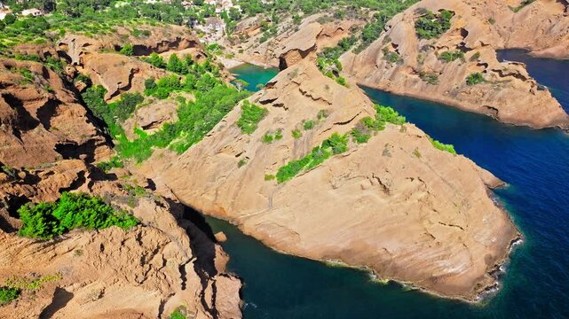 Aerial view of Tourist attraction beach, people enjoying summer vacation in Parc du Mugel, France. Snug Cove framed by rugged cliffs, with calm swimming off a pebble beach, and turquoise clear water.